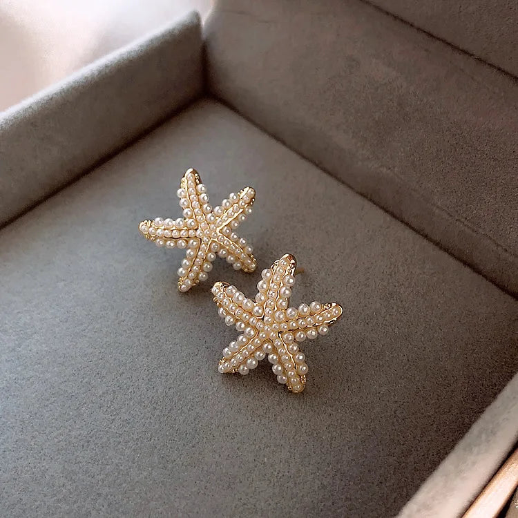 Détail des boucles d’oreilles Nérée dorées en acier inoxydable, texture étoile de mer et perles raffinées, bijou poétique et lumineux.