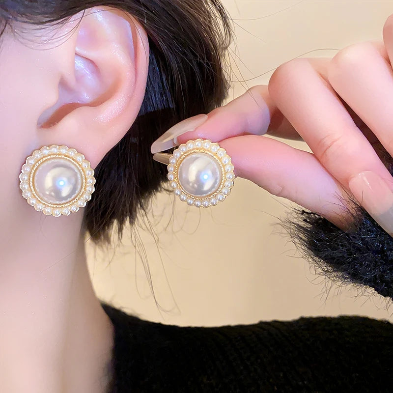 Boucles d’oreilles Euphémia dorées, design raffiné avec perles lumineuses, mises en valeur sur une tenue chic.