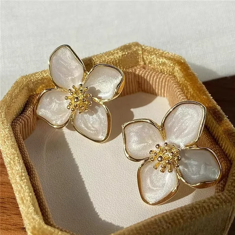 Boucles d’oreilles Séléné en acier inoxydable doré, forme de fleur délicate, sublimées par des pétales en nacre pour un éclat doux.