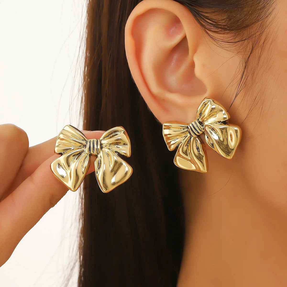 Boucles d’oreilles Lysimache en acier inoxydable doré, bijou imposant en forme de nœud, porté pour un style sophistiqué et audacieux.