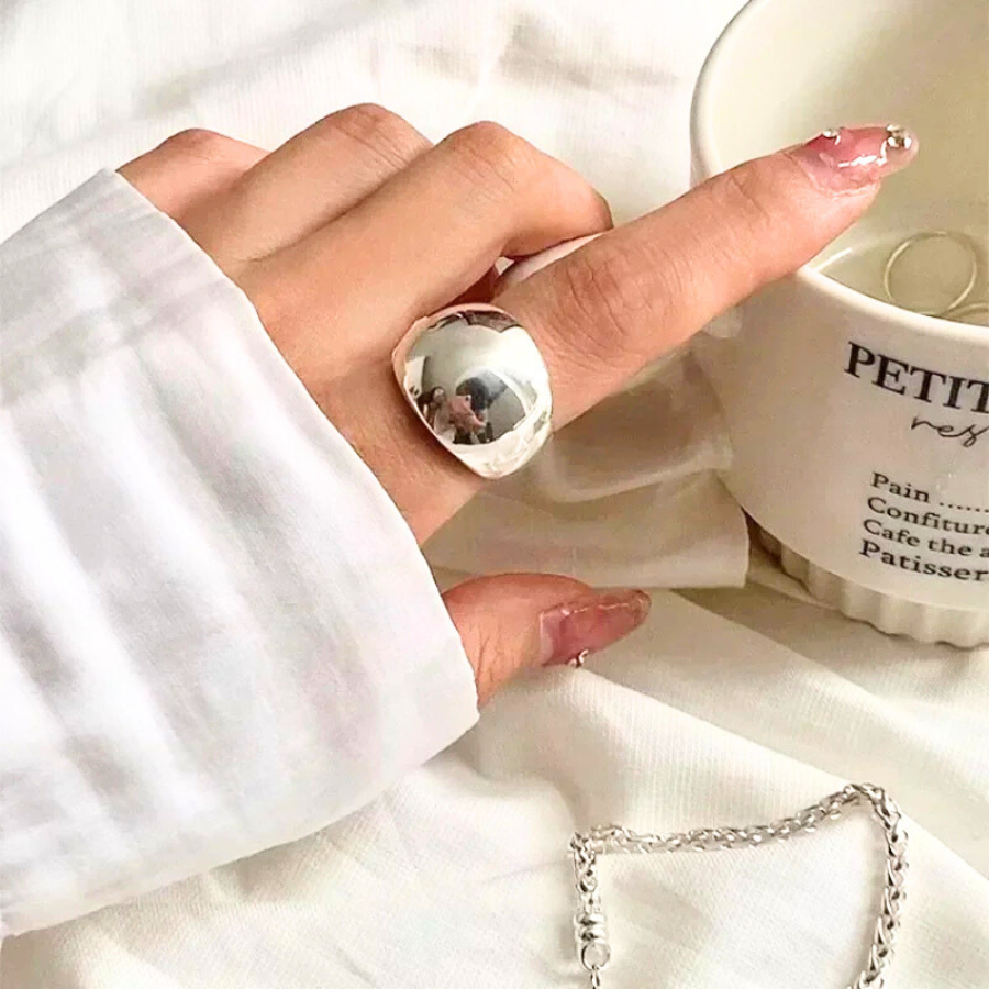 Bague femme Amphitrite en acier inoxydable argenté, bijou ajustable au design large et épuré, portée pour un style sophistiqué.
