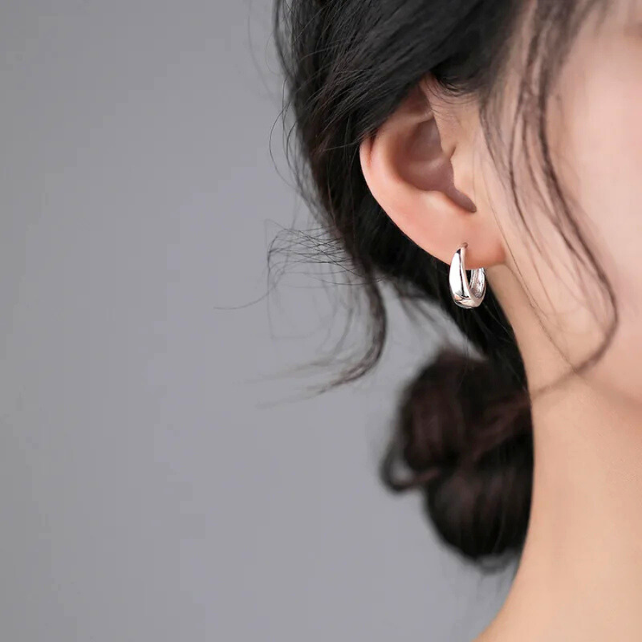 Boucles d’oreilles Cassiopeia argentées, anneaux élégants et épurés portés pour une touche de sophistication discrète.