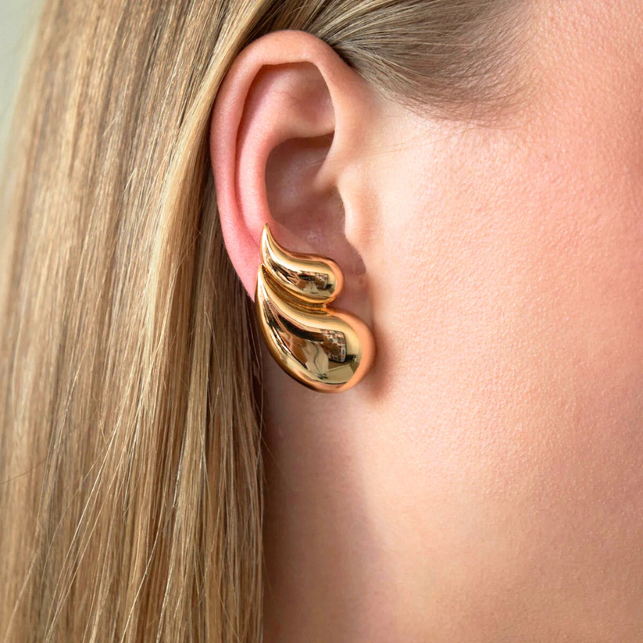 Boucles d’oreilles Aglaia en acier inoxydable doré, bijou raffiné en forme de double goutte d’eau, porté pour un style élégant et sophistiqué.
