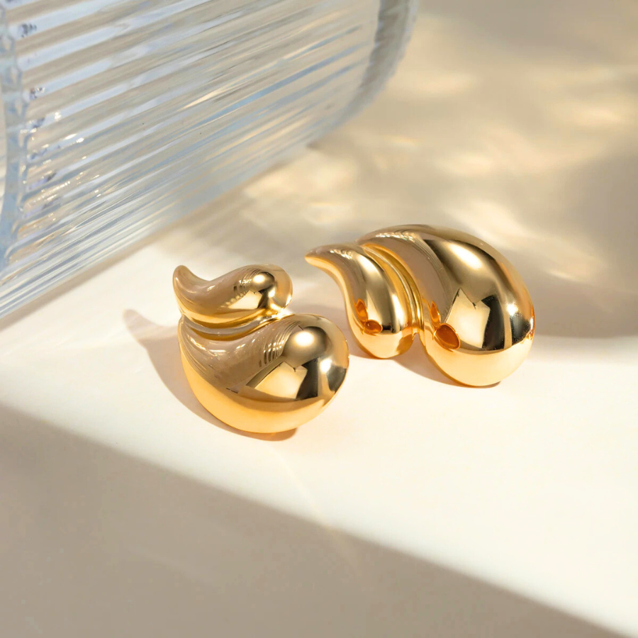 Détail des boucles d’oreilles Aglaia en finition dorée, mettant en valeur leur design élégant de double goutte d’eau.