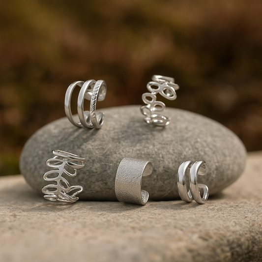Coffret de 5 earcuffs argentés en acier inoxydable chirurgical posés sur une pierre, bijoux sans perçage L’Écrin d’Éclat.