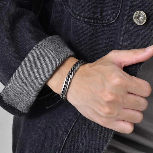 Bracelet homme Thanatos en acier inoxydable argenté mat, avec maille gourmette robuste, porté pour un style puissant et élégant.