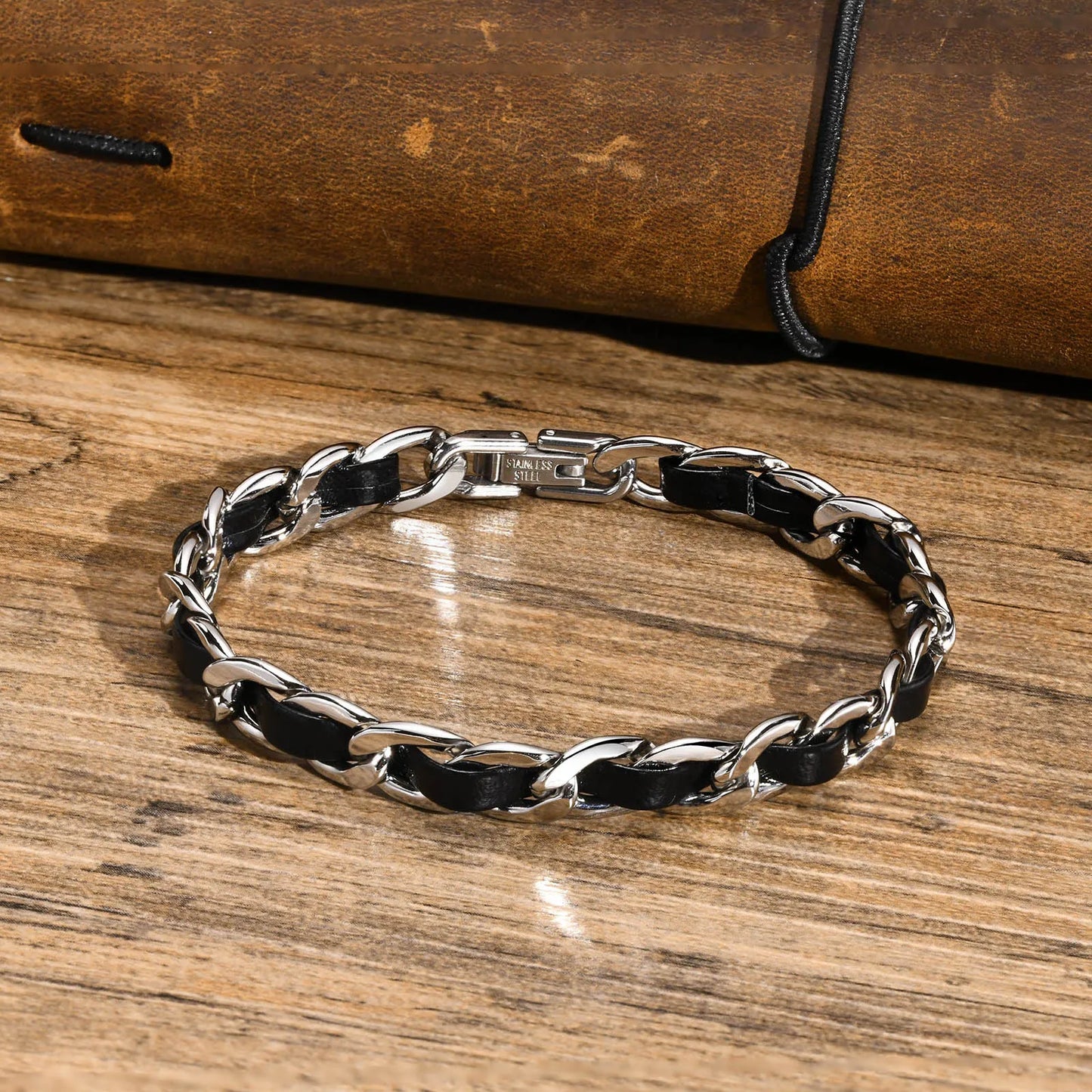 Bracelet homme Éole en acier inoxydable argenté avec lanière en cuir noir tressé, accessoire chic et intemporel.