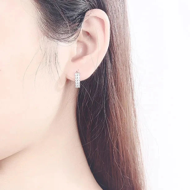 Boucles d’oreilles Amphissa en acier inoxydable argenté, petits anneaux sertis de brillants scintillants, portés pour un style raffiné et lumineux.