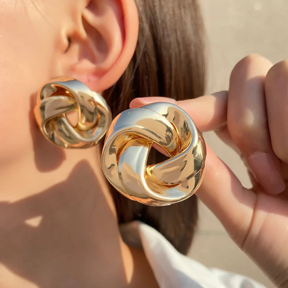 Boucles d’oreilles Arctia en acier inoxydable doré, bijou imposant en forme de nœud, porté pour un style audacieux et élégant.