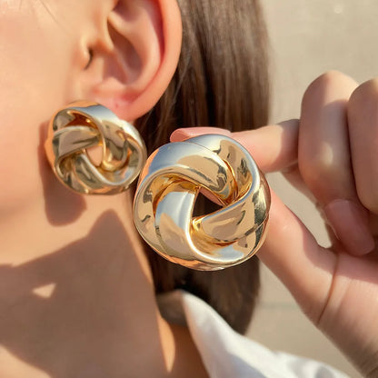 Boucles d’oreilles Arctia en acier inoxydable doré, bijou imposant en forme de nœud, porté pour un style audacieux et élégant.