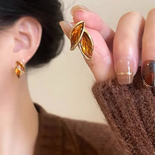 Boucles d’oreilles Thalassa en acier inoxydable doré, design en forme de feuille avec effet nacré, portées avec élégance.