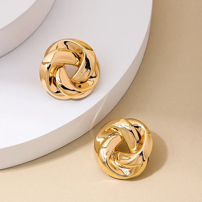Boucles d’oreilles Arctia dorées, bijou moderne et imposant en forme de nœud, parfait pour un look chic et tendance.