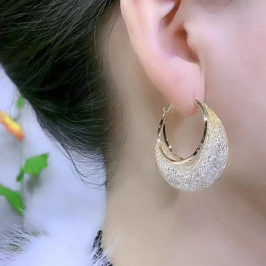 Boucles d’oreilles Laodicé en acier inoxydable doré, créoles élégantes ornées de strass scintillants, portées pour un style glamour et raffiné.