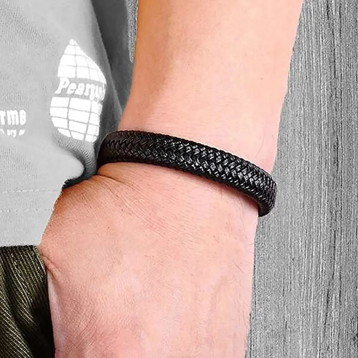 Bracelet homme Harès en cuir tressé noir, avec fermoir noir en acier inoxydable, porté pour un look puissant et sophistiqué.
