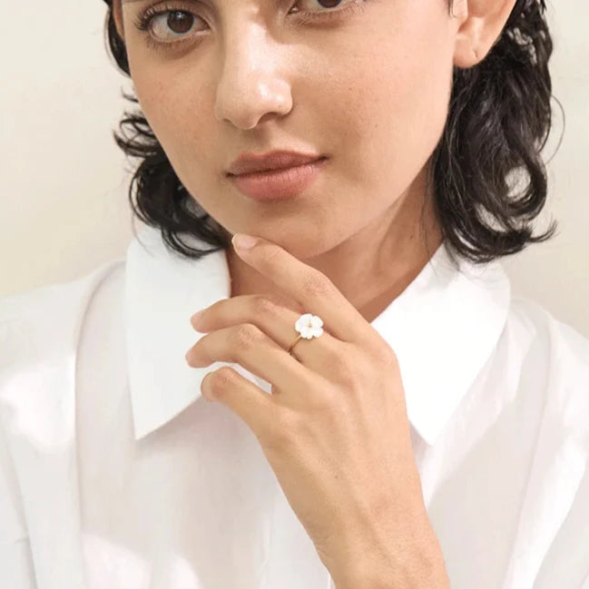 Bague femme Eurynome en acier inoxydable doré, bijou ajustable fin et raffiné, sublimé par une fleur blanche lumineuse, portée pour un style délicat et féminin.