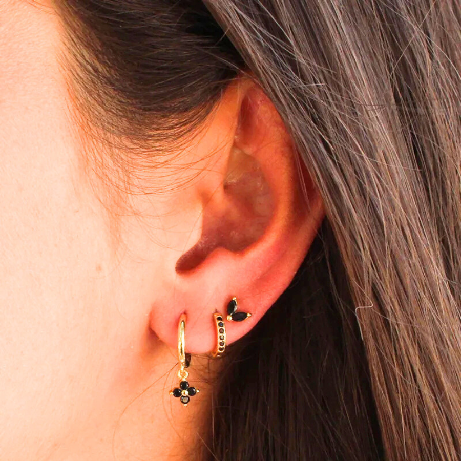 Boucles d’oreilles Cléophée en acier inoxydable doré avec strass noirs, portées avec élégance.