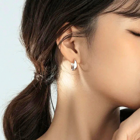 Boucles d’oreilles Cassiopeia en acier inoxydable argenté, anneaux évasés modernes portés pour un style raffiné et minimaliste.