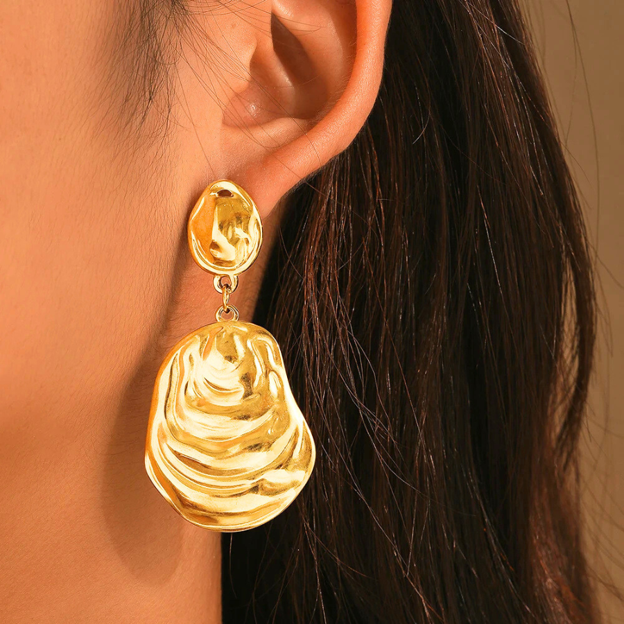 Boucles d’oreilles Andromaque en acier inoxydable doré, bijou ondulé et pendantes, porté pour un style chic et contemporain.