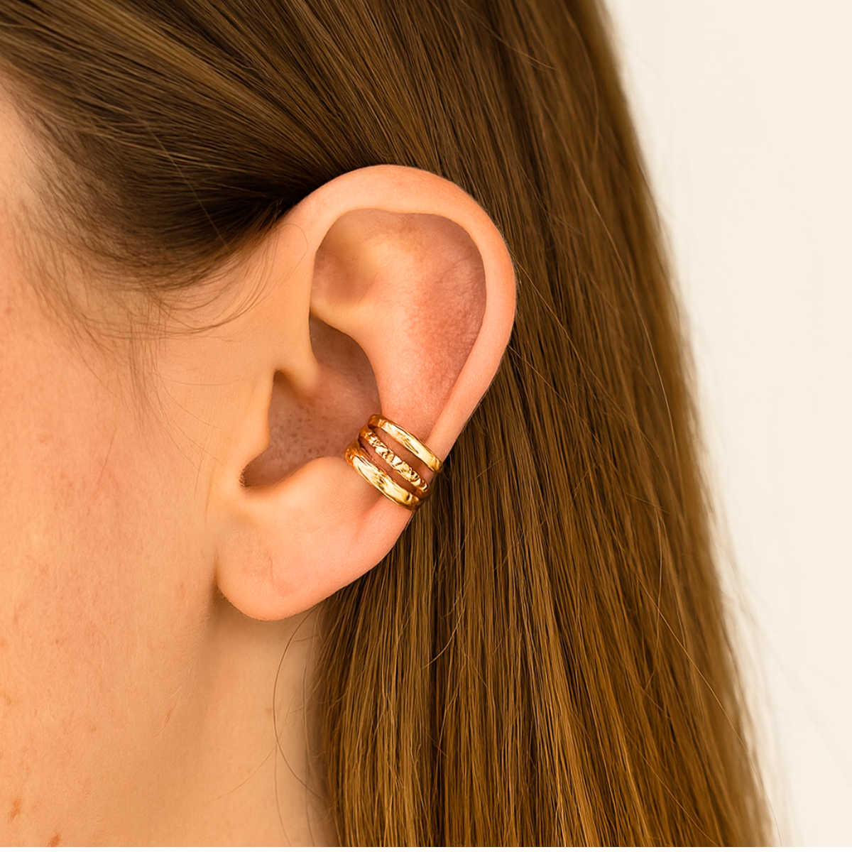 Paire d'ear cuffs Trio Harmonie dorés sans perçage portés sur l'oreille