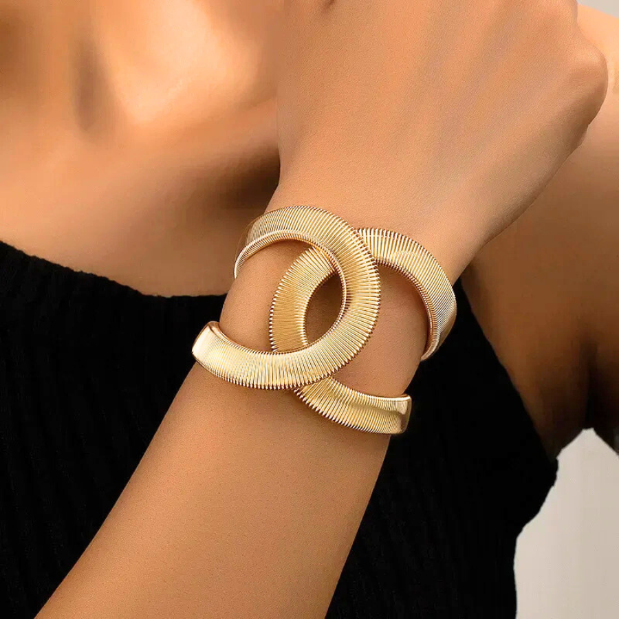 Bracelet jonc Phaedra en acier inoxydable doré, avec maille serpent plate, porté au poignet pour un look moderne et élégant.