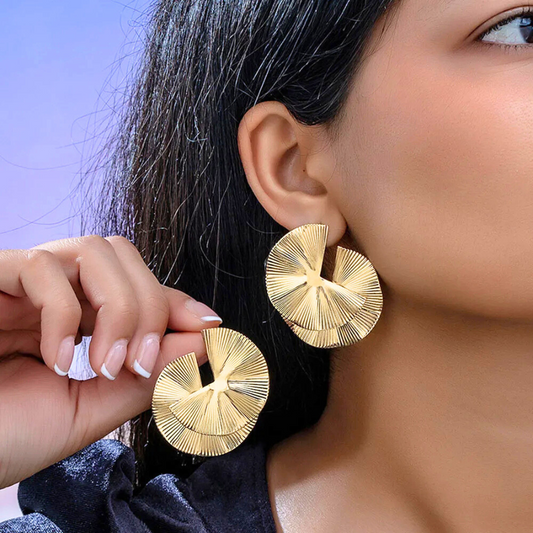 Boucles d’oreilles Mnémé en acier inoxydable doré, bijou audacieux en demi-fleurs, porté pour un style moderne et sophistiqué.